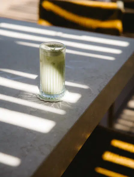 Cocktail matcha latte du bar Indie Beach Pampelonne servi sur comptoir pierre au soleil